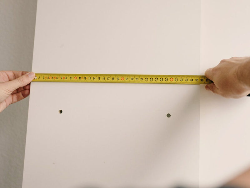 Aufmaß an der Wand mit Maßband vor dem Möbelaufbau (Symbolbild)
